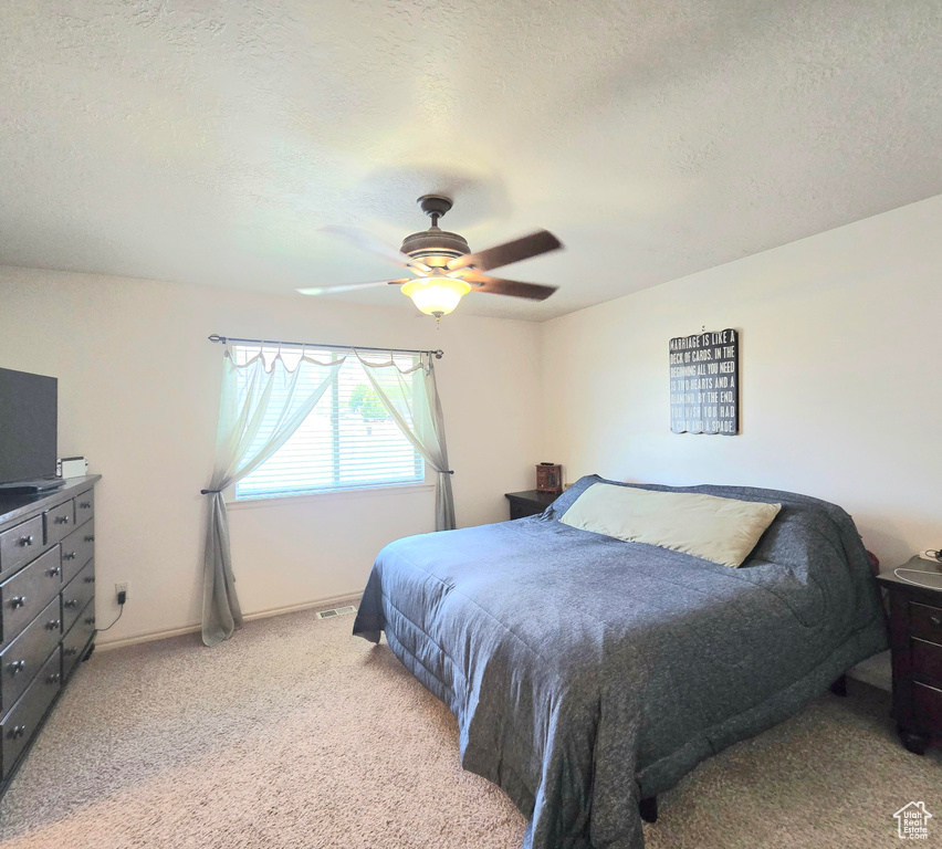 Bedroom featuring light colored carpet, a textured ceiling, ceiling fan, and baseboards