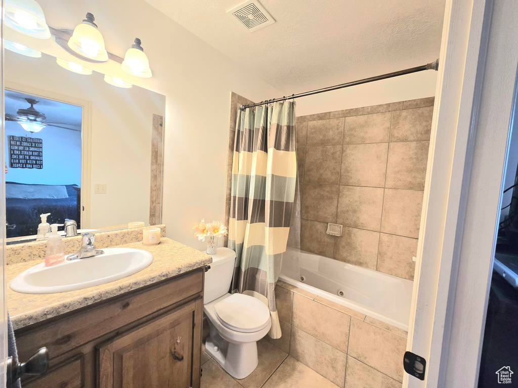 Full bathroom featuring a combined bath / shower with jetted tub, vanity, toilet, tile patterned flooring, and ensuite bath