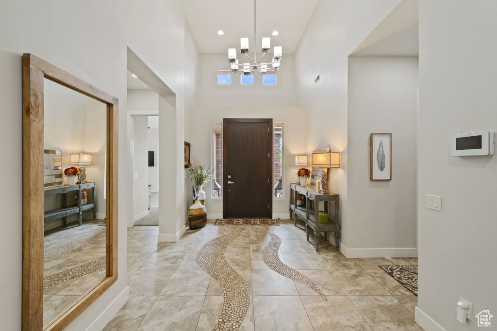 Foyer entrance with a chandelier, a high ceiling, baseboards, and recessed lighting