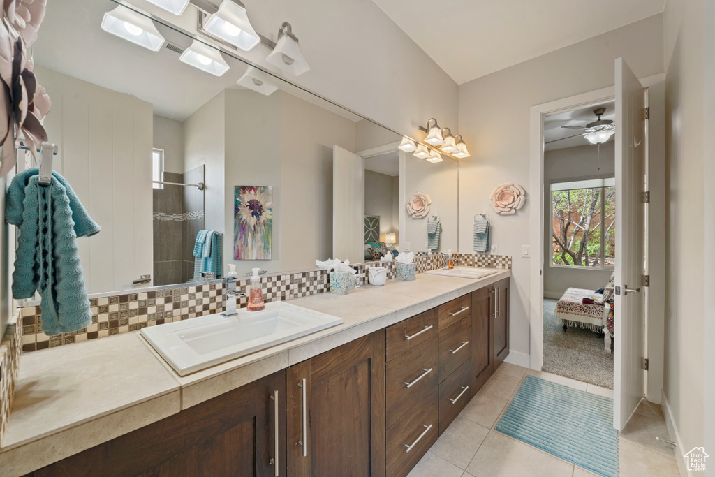 Bathroom with ceiling fan, a sink, backsplash, and double vanity