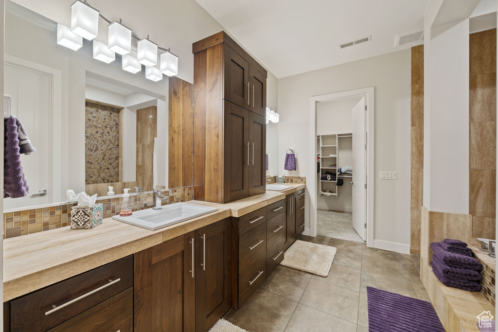 Bathroom featuring decorative backsplash, visible vents, and vanity