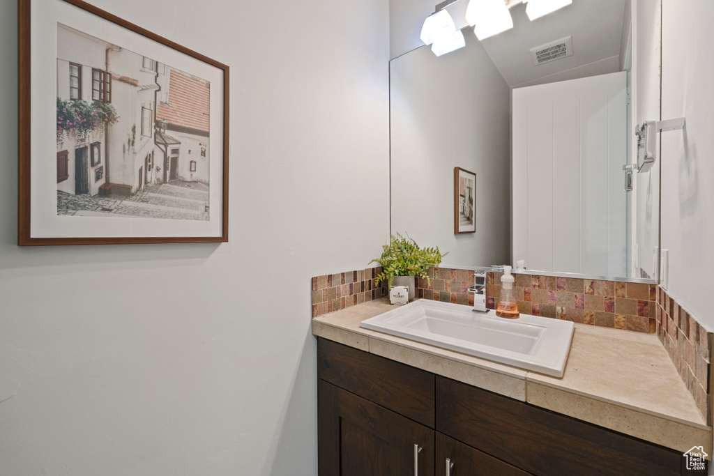Bathroom with backsplash, vanity, and visible vents