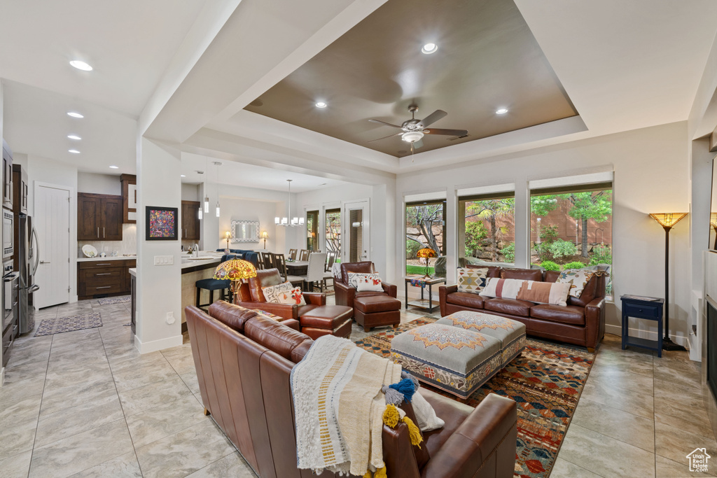 Living room featuring a tray ceiling, baseboards, ceiling fan, and recessed lighting