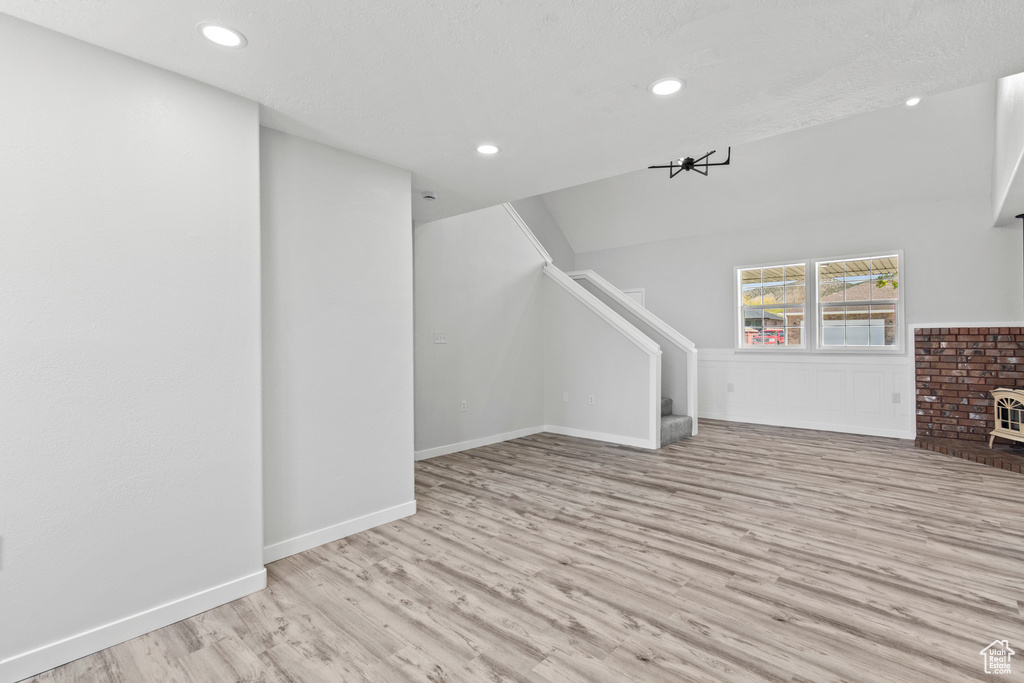 Unfurnished living room with baseboards, recessed lighting, wood finished floors, and stairs