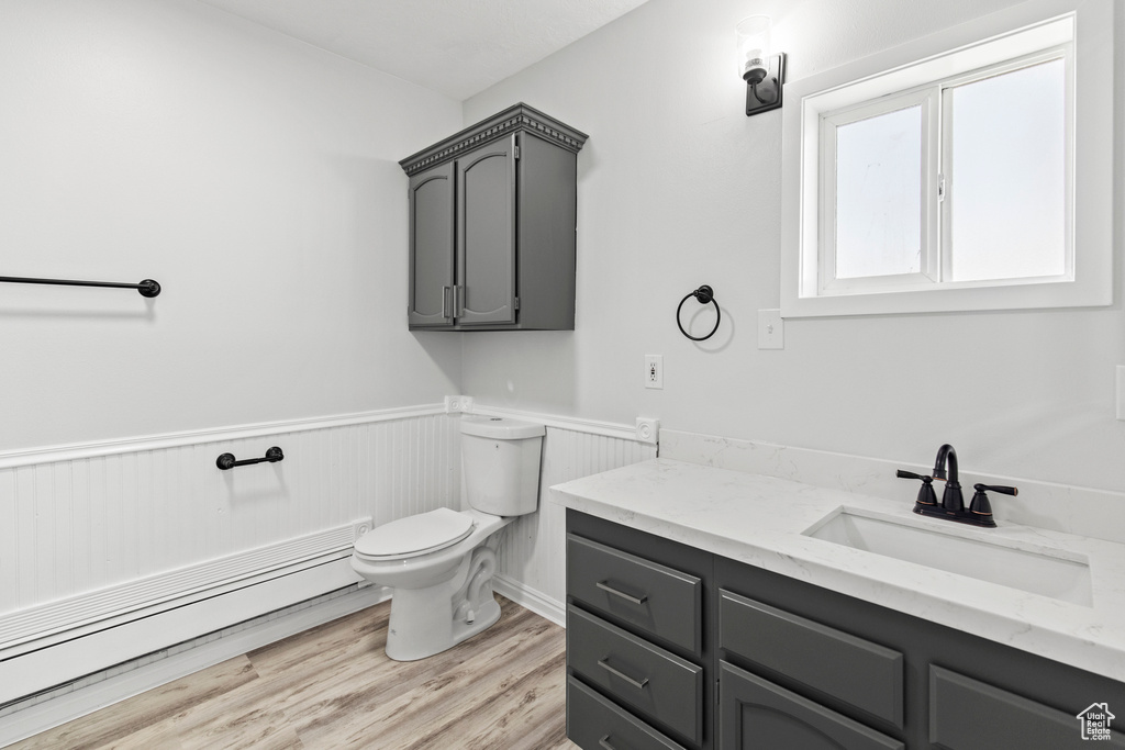Bathroom with toilet, a wainscoted wall, wood finished floors, and vanity