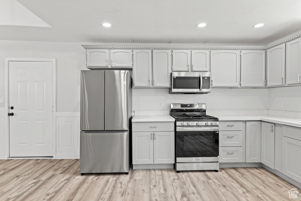 Kitchen featuring stainless steel appliances, light countertops, light wood finished floors, and recessed lighting