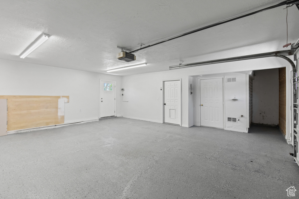 Garage featuring visible vents and a garage door opener