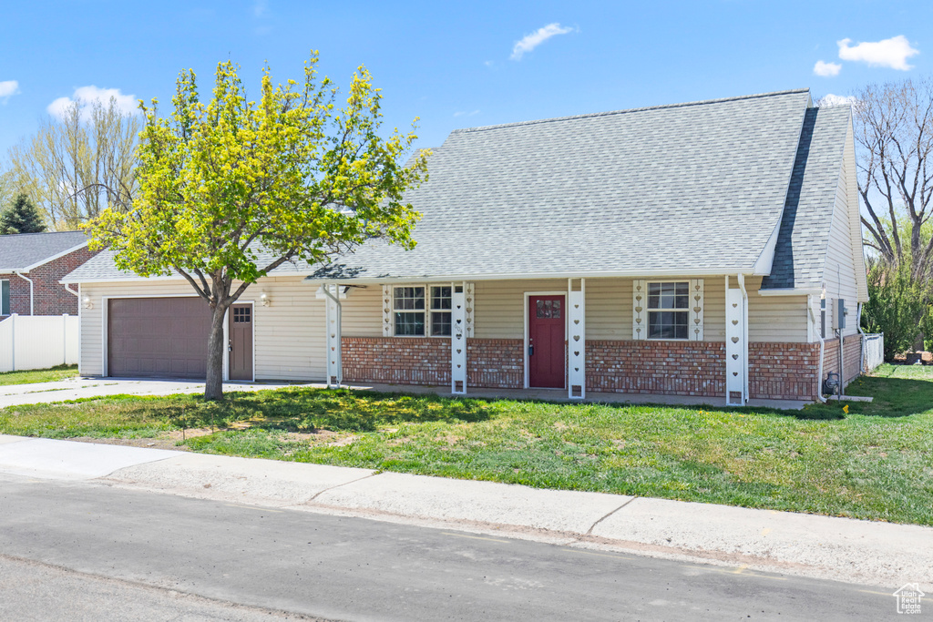 View of front of property with a garage, brick siding, a porch, and a front yard