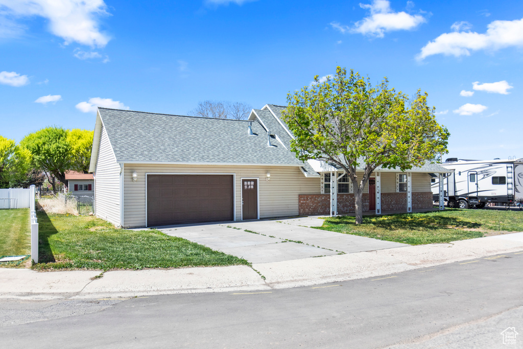 View of front of house featuring roof with shingles, a front lawn, and a garage