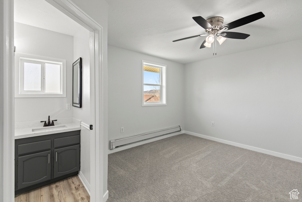 Interior space with a ceiling fan, a sink, baseboards, and a baseboard radiator