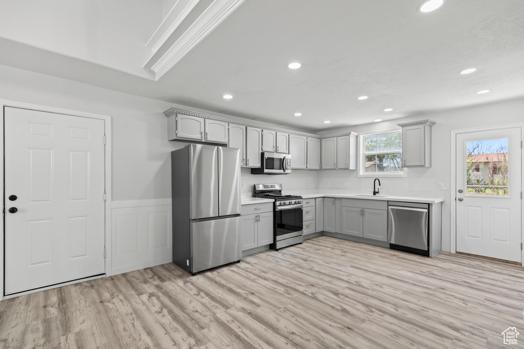 Kitchen with stainless steel appliances, recessed lighting, light wood finished floors, and gray cabinets
