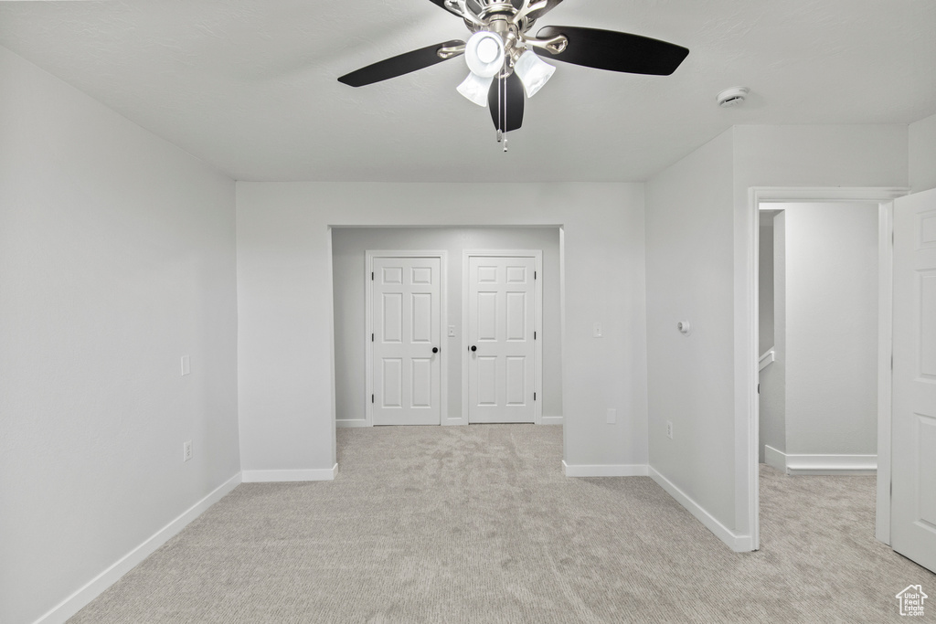 Unfurnished bedroom with baseboards, a ceiling fan, and light carpet