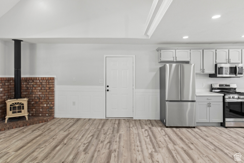 Kitchen featuring light wood finished floors, a wainscoted wall, and stainless steel appliances