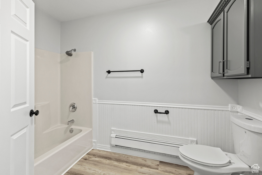 Bathroom with a wainscoted wall, toilet, and shower / tub combination