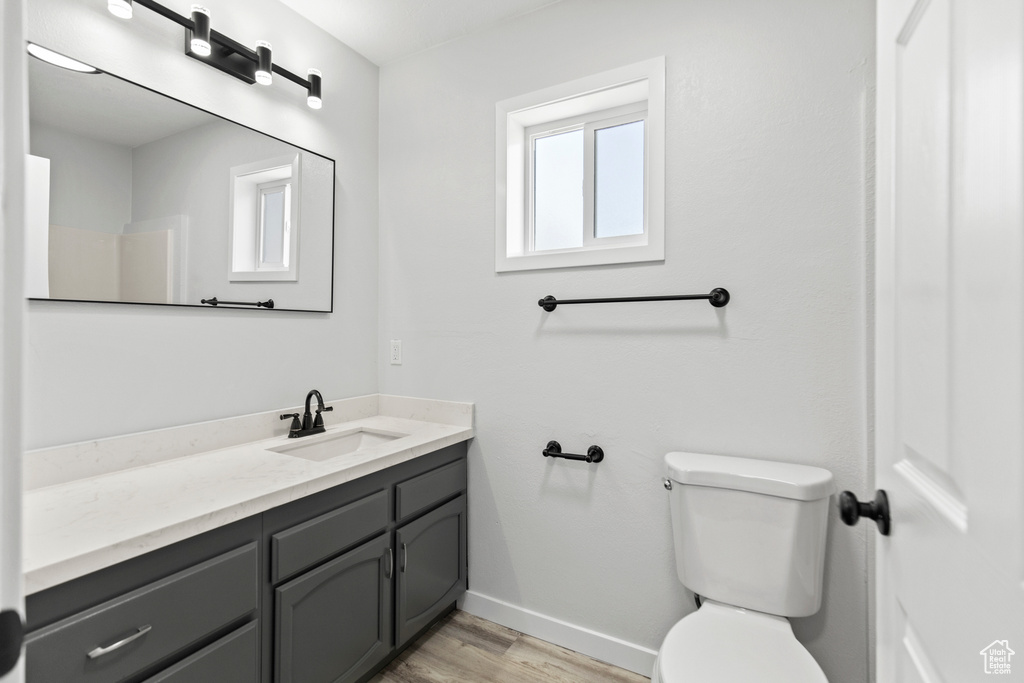 Bathroom featuring wood finished floors, toilet, vanity, and baseboards
