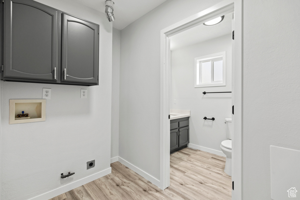 Laundry room with light wood-style flooring, electric dryer hookup, cabinet space, and washer hookup