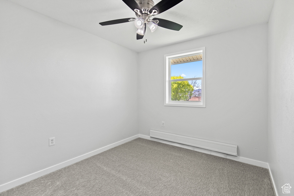 Carpeted empty room with a ceiling fan, baseboard heating, and baseboards