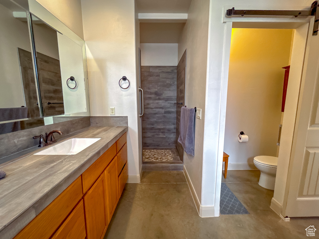 Full bathroom featuring toilet, baseboards, vanity, and a stall shower