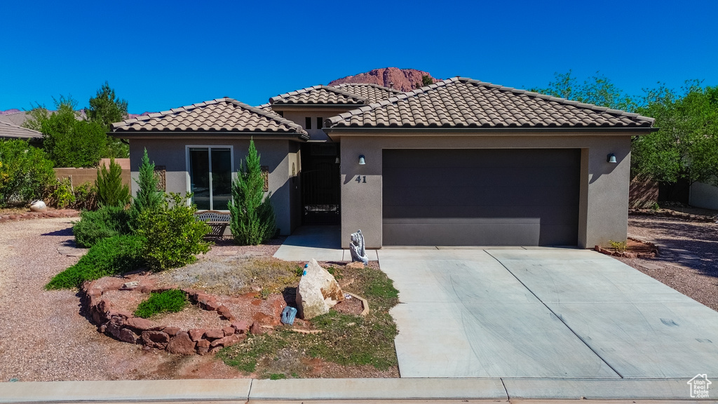 Mediterranean / spanish house with stucco siding, concrete driveway, a tiled roof, and a garage