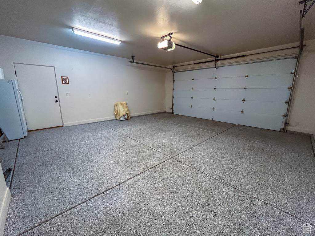 Garage with baseboards, freestanding refrigerator, and a garage door opener