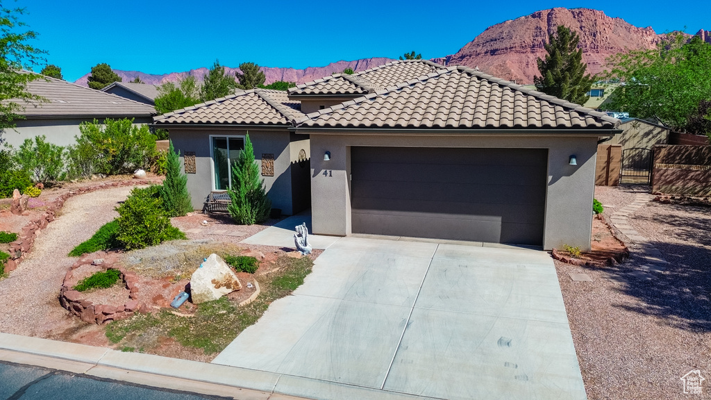 Mediterranean / spanish-style house featuring a tile roof, driveway, a mountain view, a garage, and stucco siding