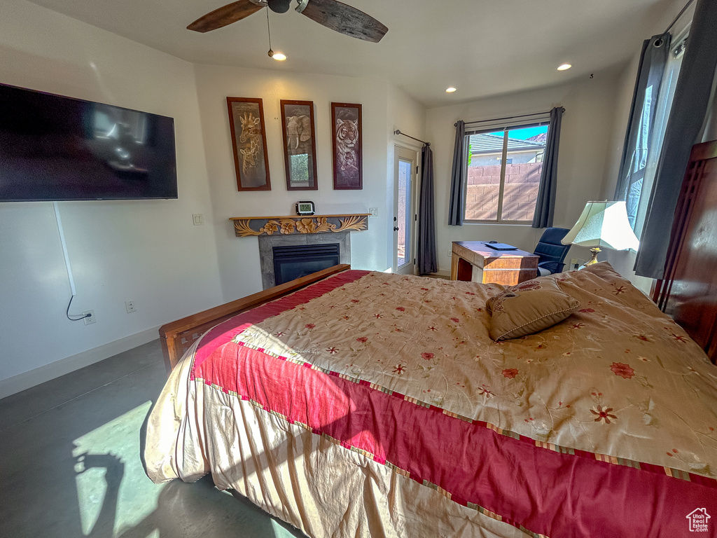 Bedroom featuring a glass covered fireplace, baseboards, finished concrete floors, recessed lighting, and a ceiling fan
