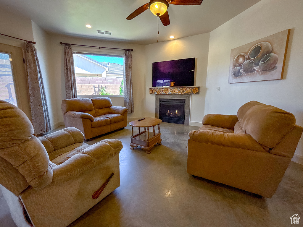 Living room featuring concrete floors, ceiling fan, a lit fireplace, baseboards, and visible vents
