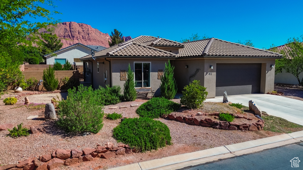 View of front of property featuring driveway, an attached garage, fence, a mountain view, and stucco siding