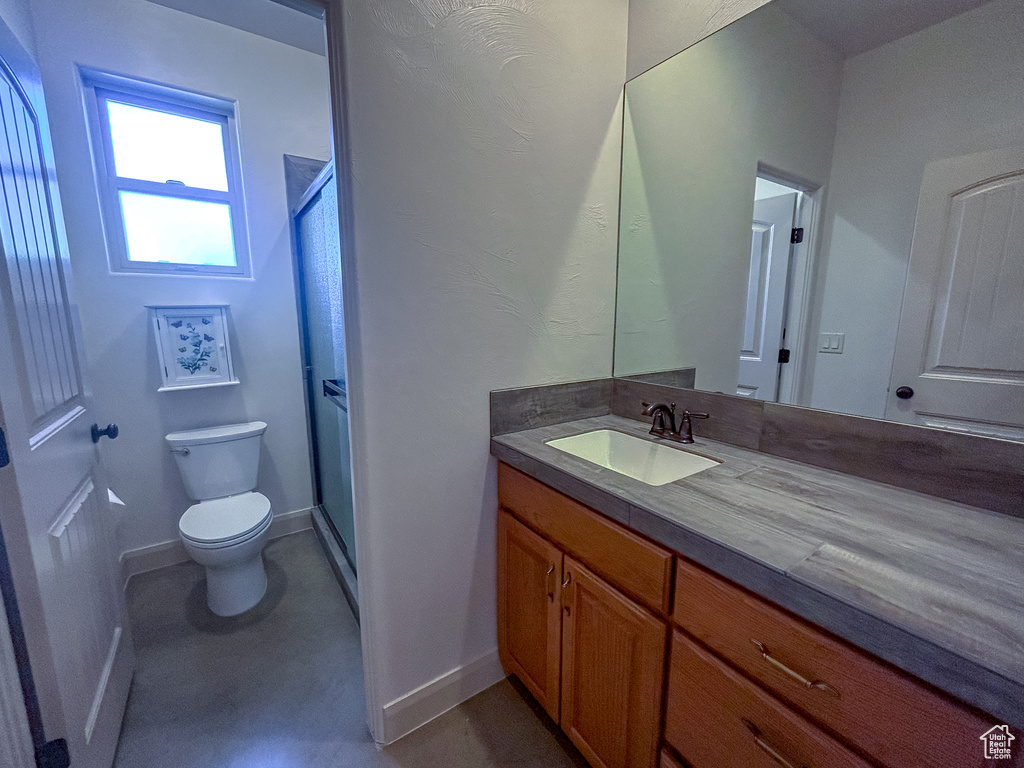 Bathroom featuring baseboards, toilet, vanity, and a stall shower