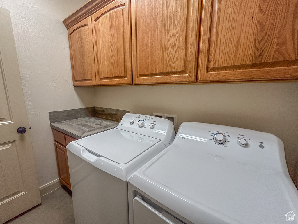 Washroom featuring light colored carpet, washer and dryer, and cabinet space