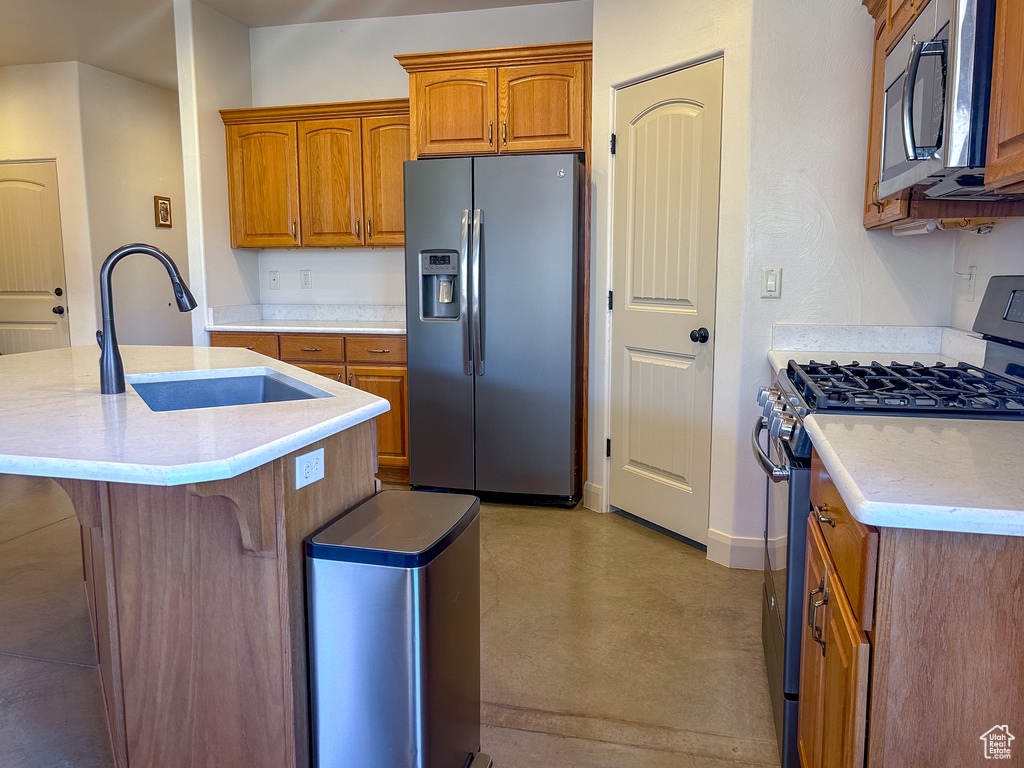 Kitchen featuring brown cabinets, a sink, concrete flooring, baseboards, and appliances with stainless steel finishes