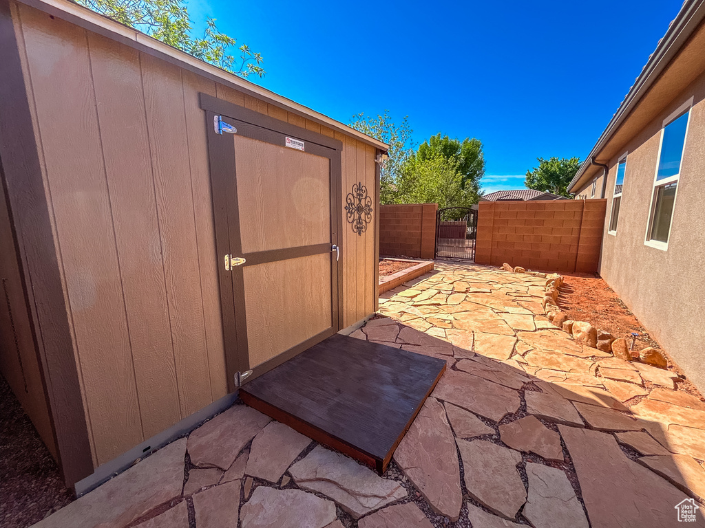 View of patio featuring a gate, a storage unit, fence, and an outdoor structure