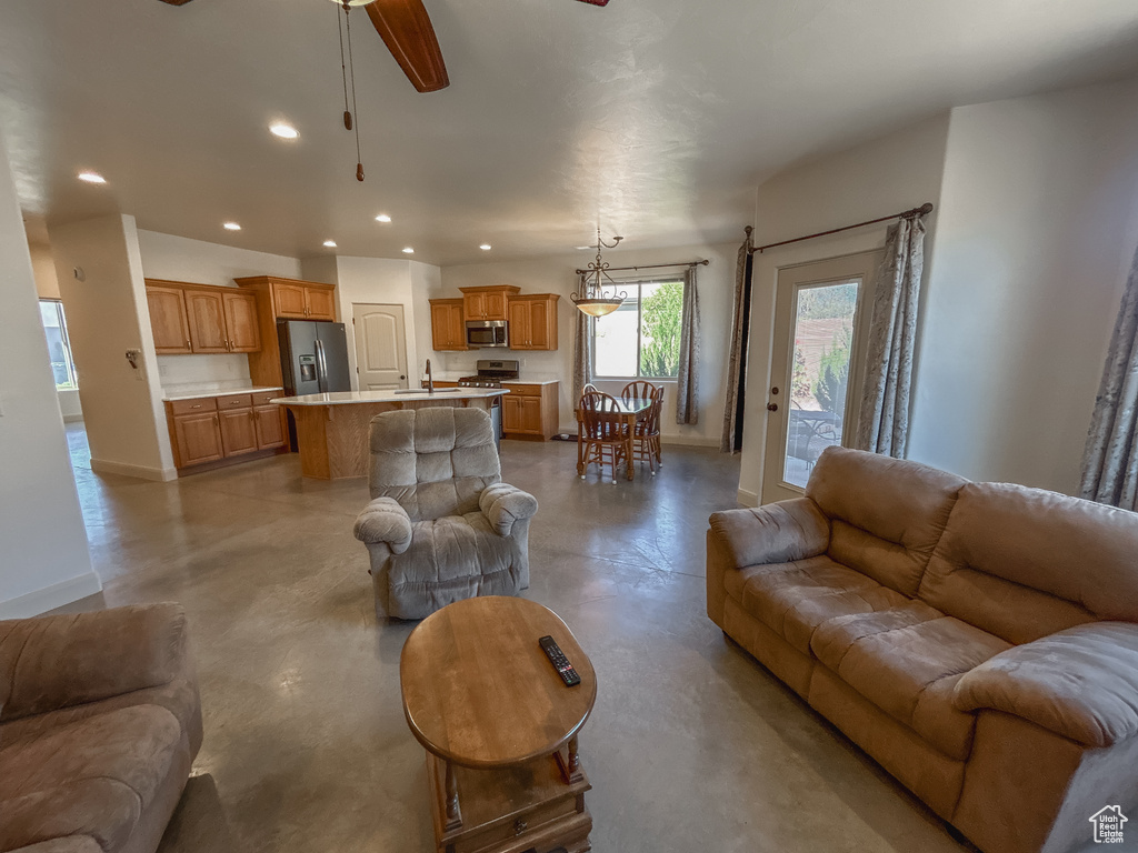 Living area featuring recessed lighting, ceiling fan, concrete floors, and baseboards