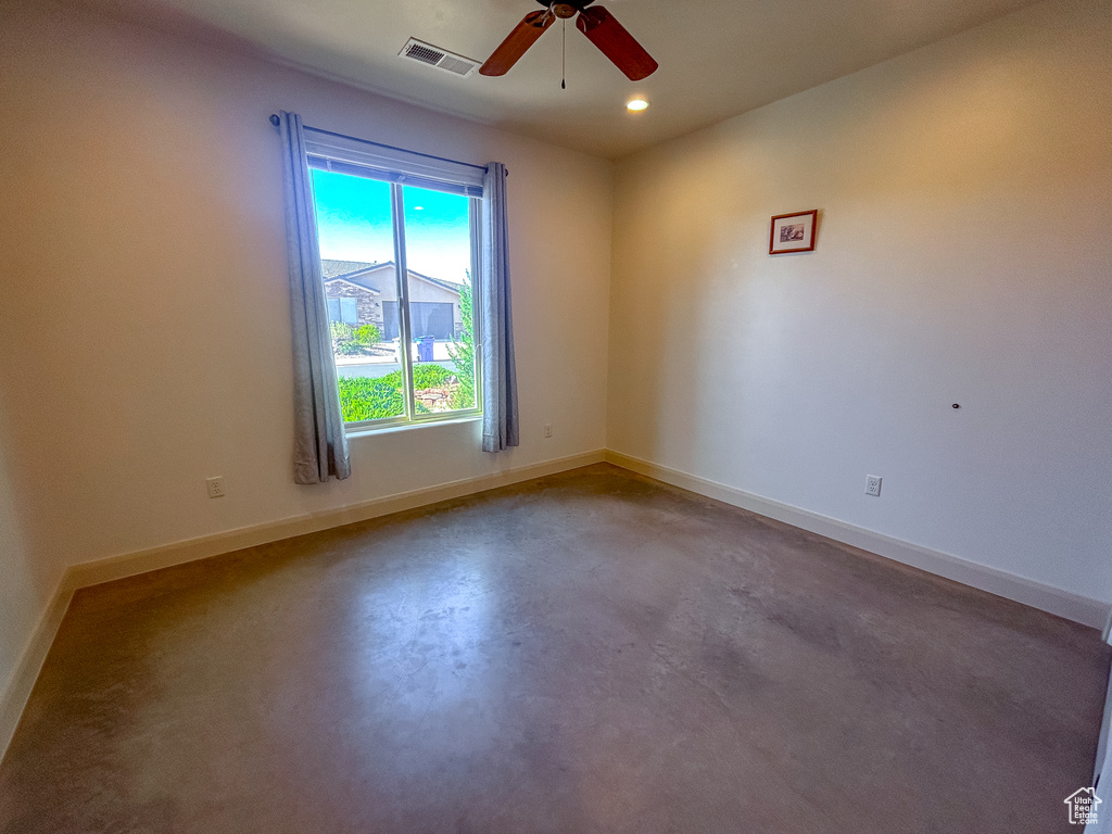 Empty room with baseboards, visible vents, concrete floors, and ceiling fan
