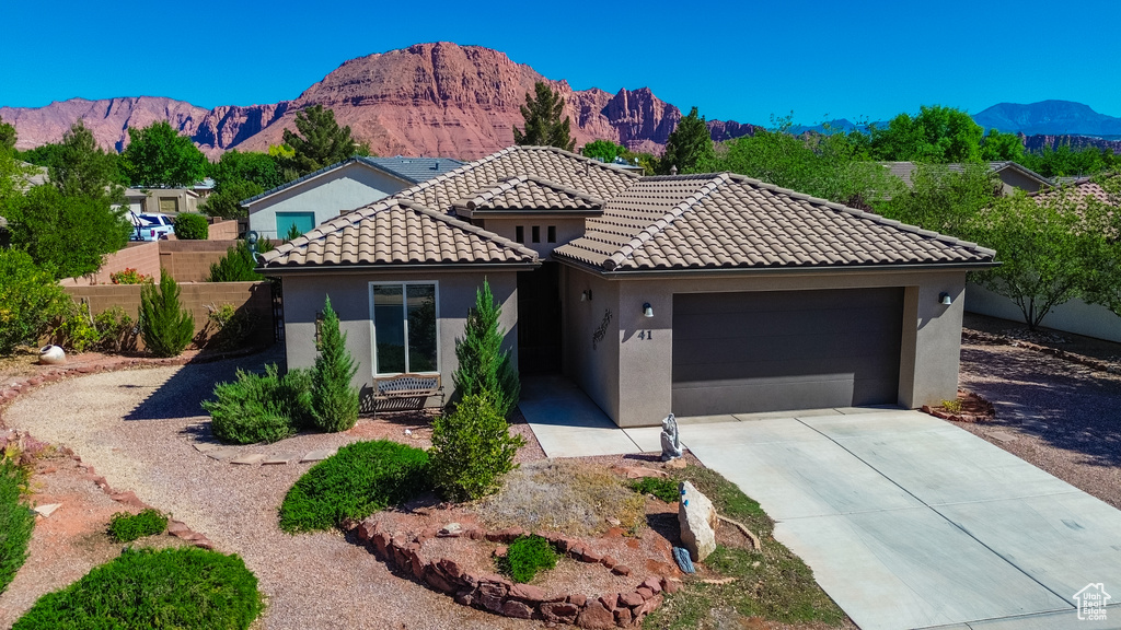 View of front of property with a tile roof, a mountain view, fence, a garage, and stucco siding