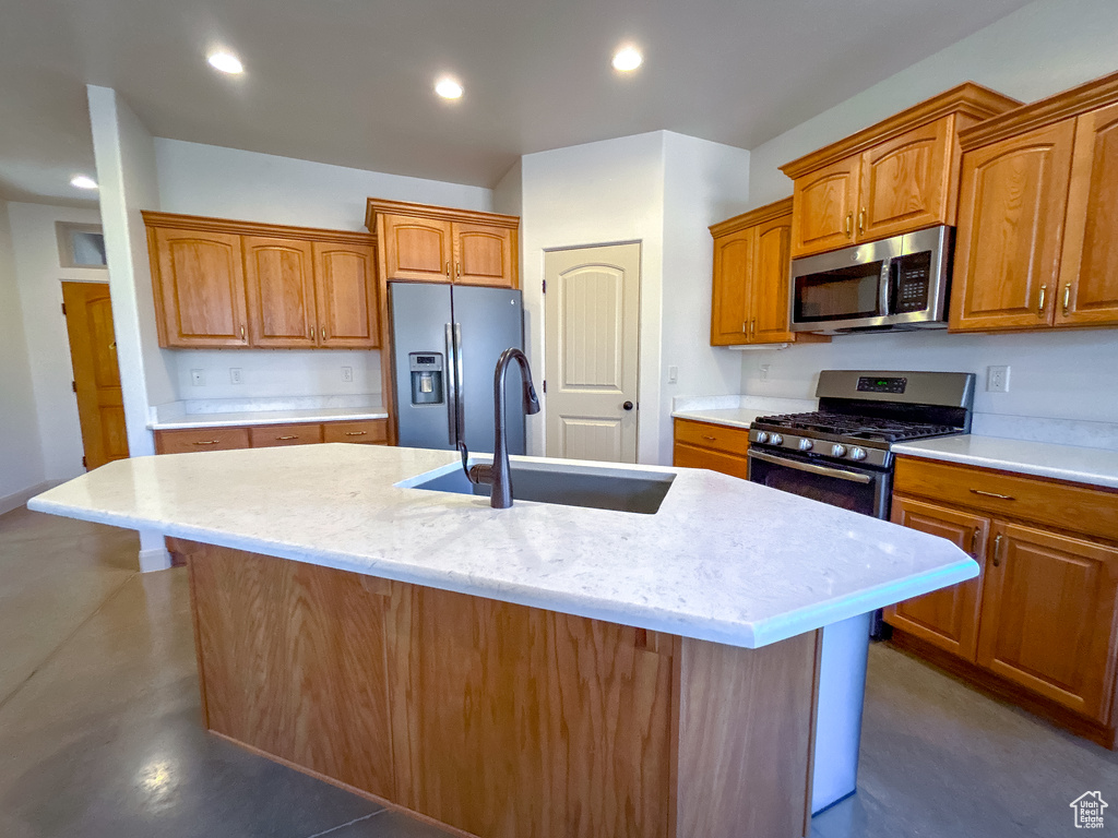 Kitchen with stainless steel appliances, brown cabinets, a sink, and an island with sink