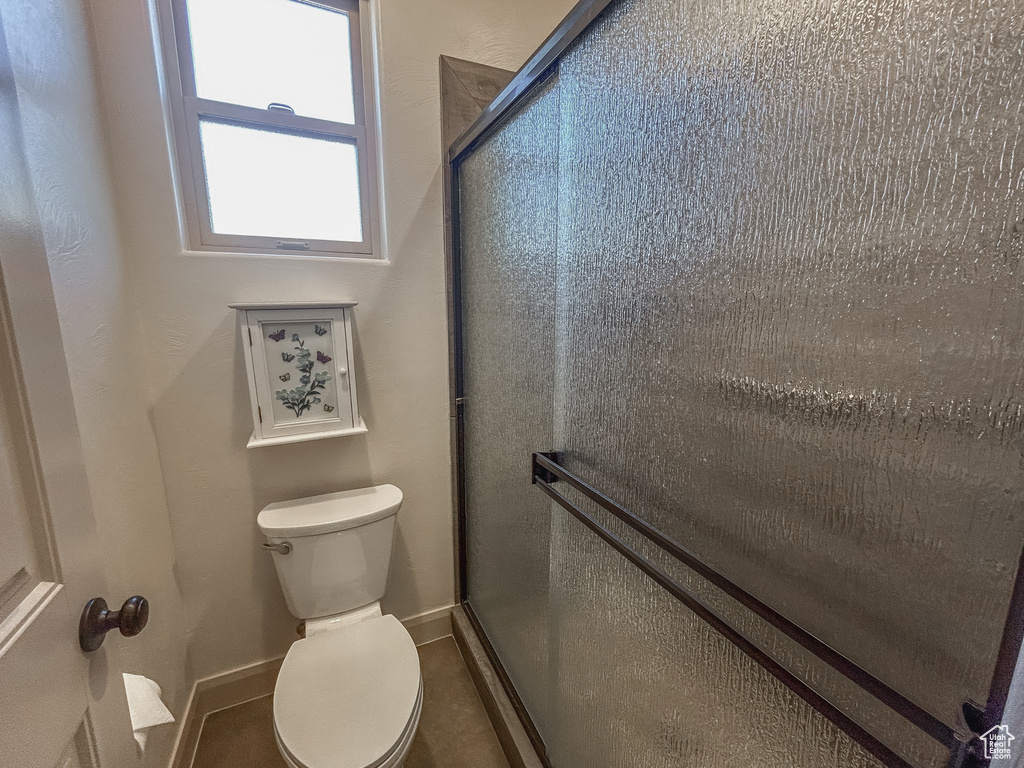 Full bathroom featuring baseboards, toilet, and a stall shower
