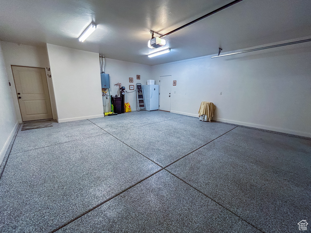 Garage with electric panel, baseboards, and a garage door opener