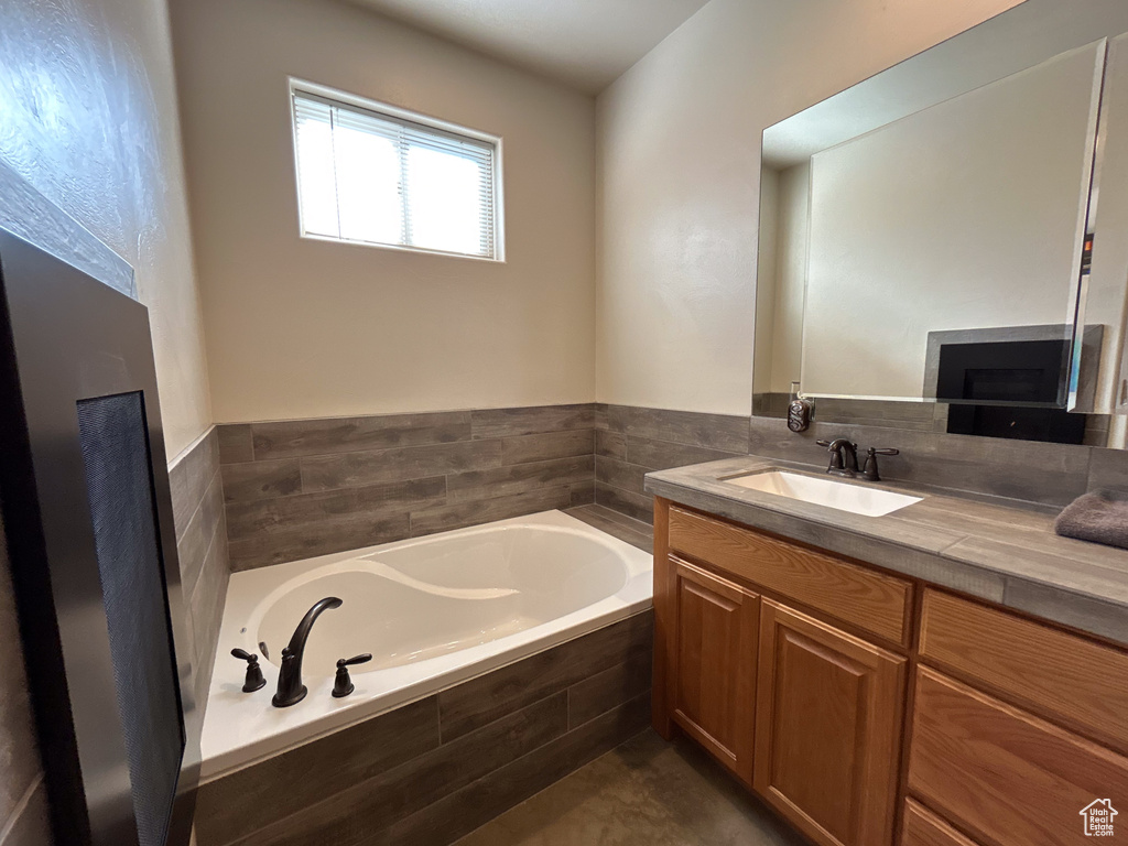 Full bathroom featuring a garden tub, vanity, and a fireplace