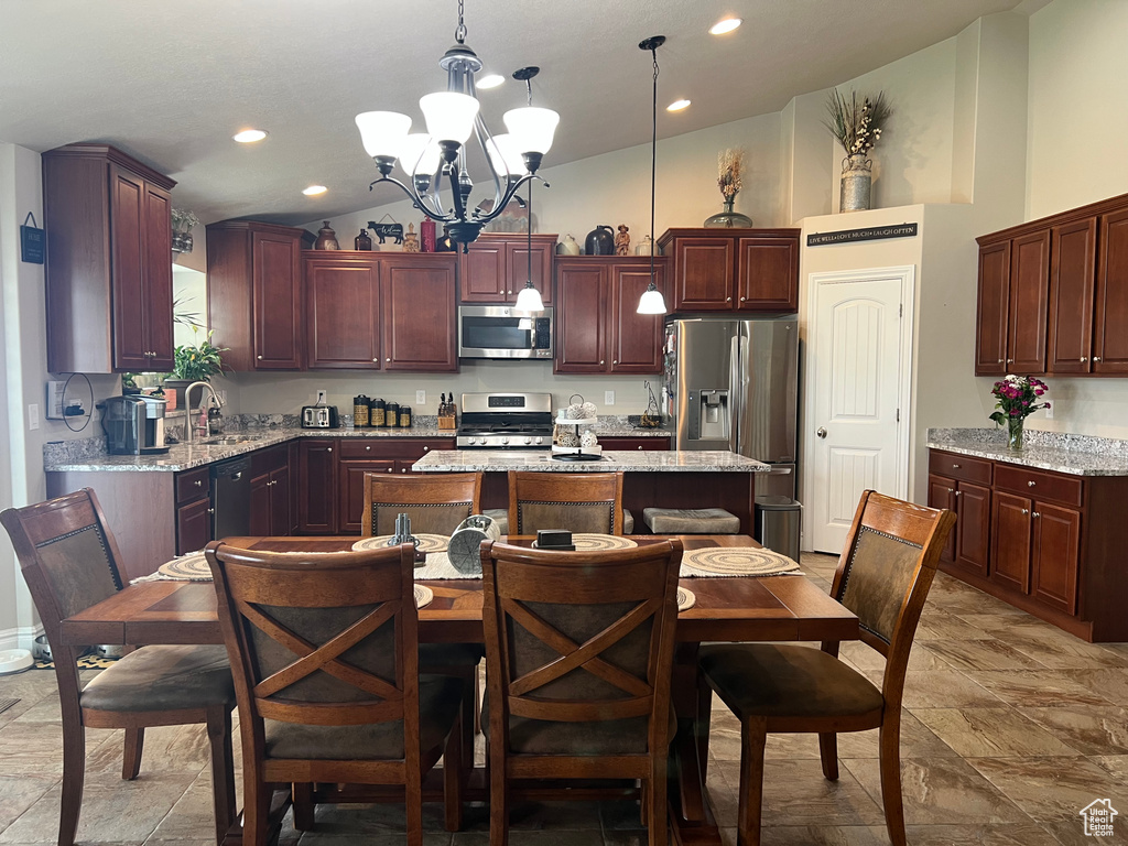 Kitchen with stainless steel appliances, a chandelier, a center island, hanging light fixtures, and a sink