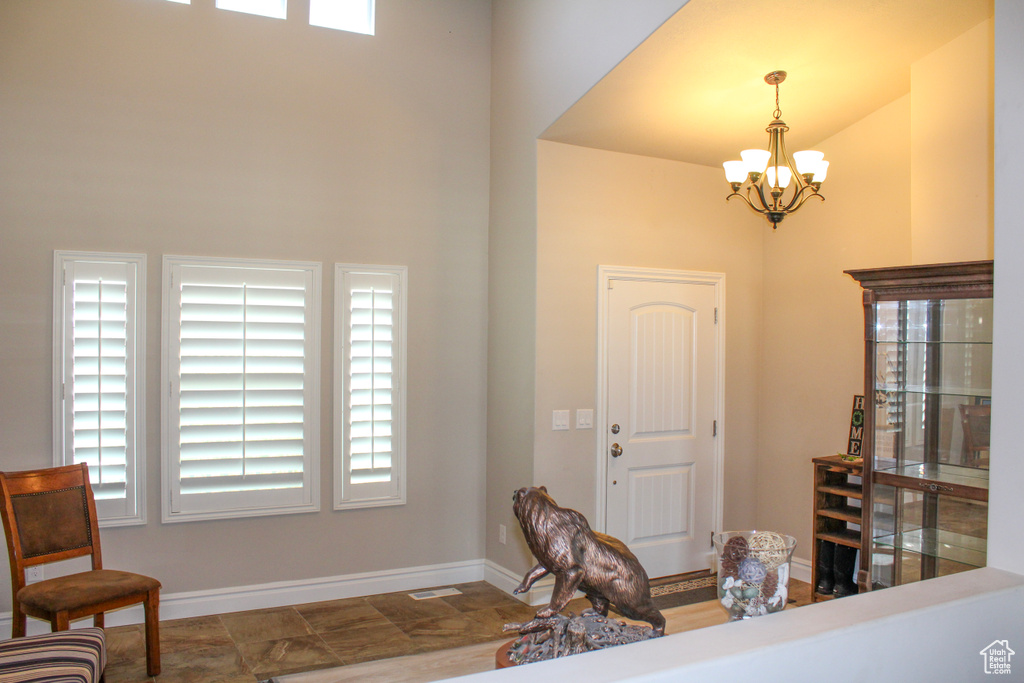 Entrance foyer featuring a chandelier, plenty of natural light, baseboards, and a towering ceiling