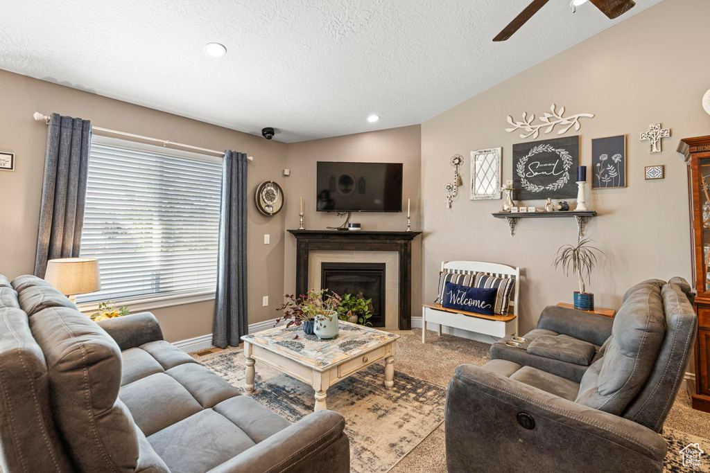 Living area with a textured ceiling, ceiling fan, a fireplace, baseboards, and carpet flooring