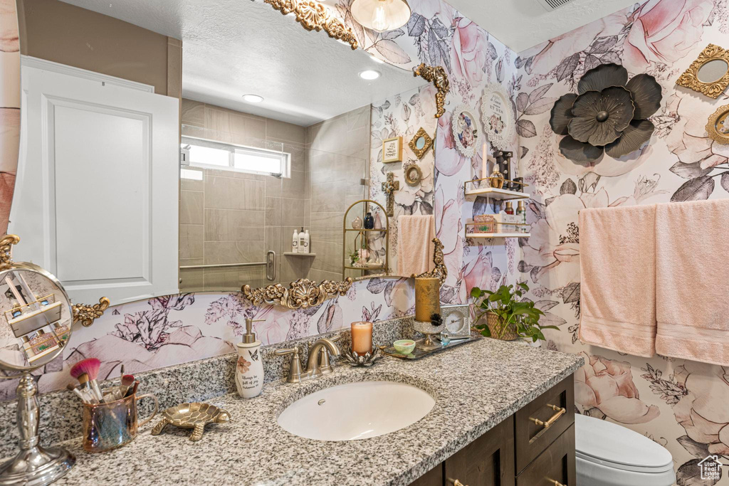 Full bathroom featuring tiled shower, vanity, and toilet