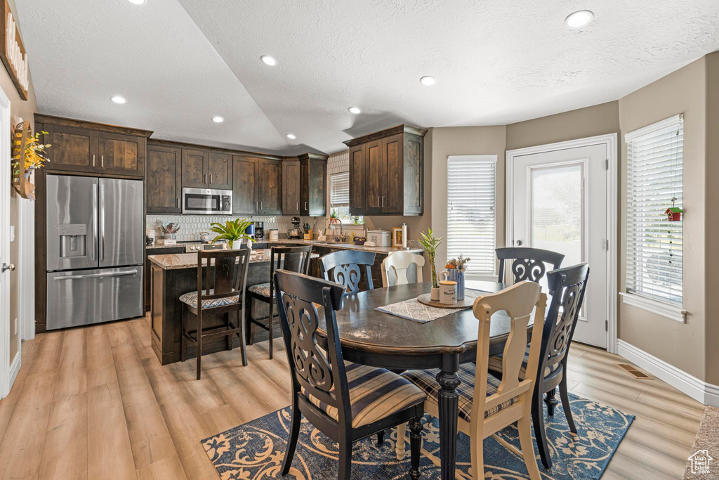 Dining area with a textured ceiling, light wood-style flooring, baseboards, visible vents, and recessed lighting