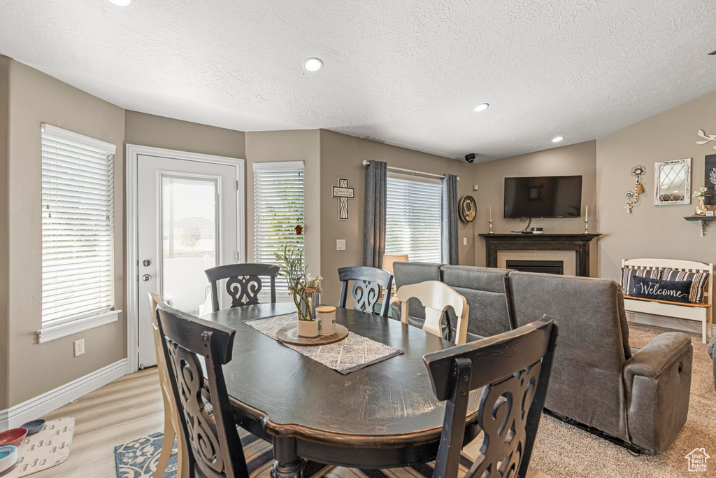 Dining area featuring light wood-style flooring, a textured ceiling, baseboards, recessed lighting, and a fireplace