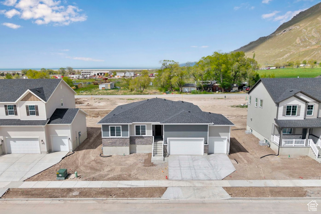 View of front of property featuring concrete driveway, a mountain view, a garage, and roof with shingles