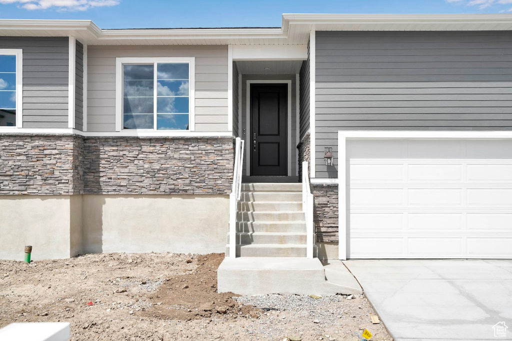 View of exterior entry featuring stone siding and a garage