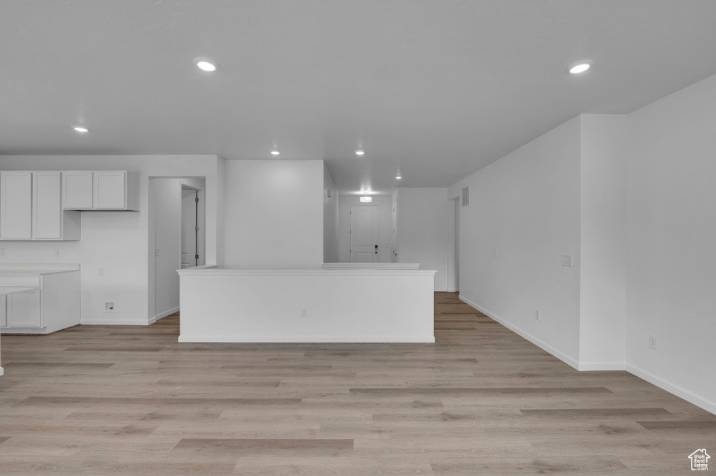 Unfurnished living room with recessed lighting, baseboards, and light wood-style flooring