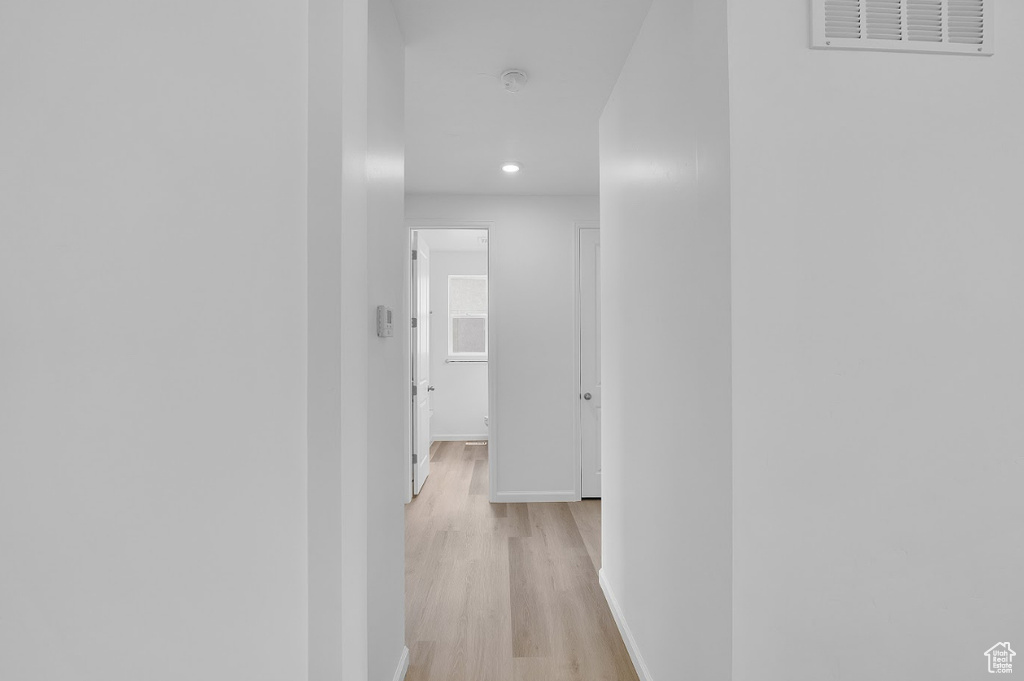 Hall featuring light wood finished floors, baseboards, and recessed lighting