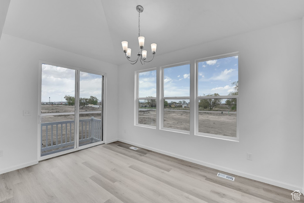 Unfurnished dining area featuring wood finished floors, a chandelier, and baseboards
